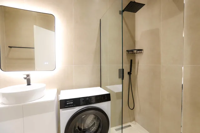 Bagno con doccia, lavabo e lavatrice