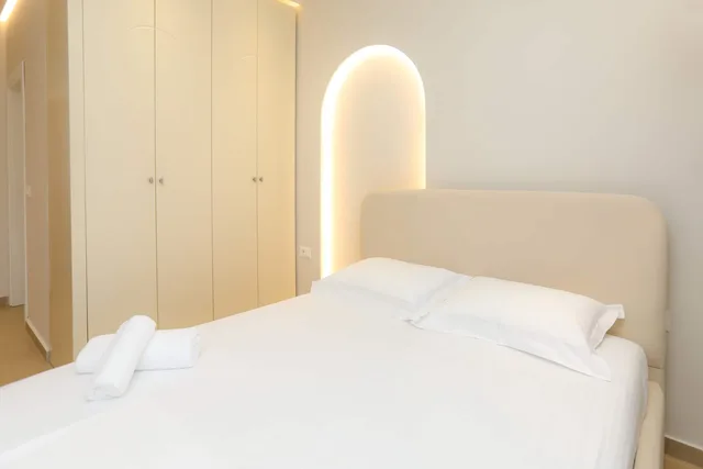 Letto matrimoniale con nicchia ad arco illuminata dietro la testiera